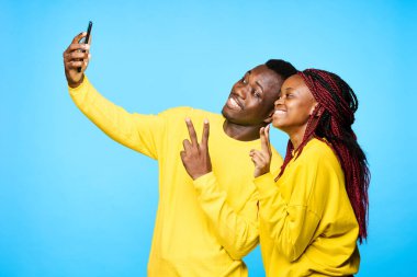 Genç ve güzel bir çift stüdyoda mavi arka planda selfie çekiyor.