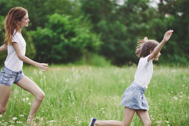 Genç anne ve kızı papatya tarlasında eğleniyorlar.