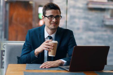 Kafede dizüstü bilgisayarla çalışan yakışıklı bir iş adamı.