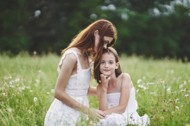 Genç anne ve kızı papatya tarlasında eğleniyorlar.