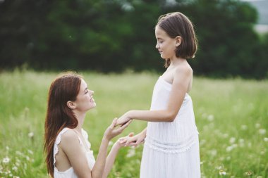Genç anne ve kızı papatya tarlasında eğleniyorlar.