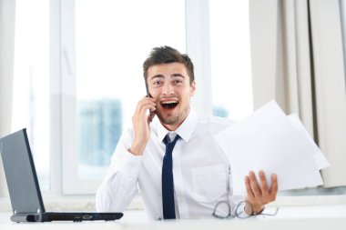 İş konsepti. Yong işadamı akıllı telefondan konuşuyor ve evrakları ofiste tutuyor. 