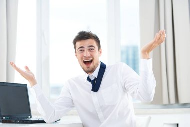 Ofiste dizüstü bilgisayarı olan mutlu genç bir iş adamı.