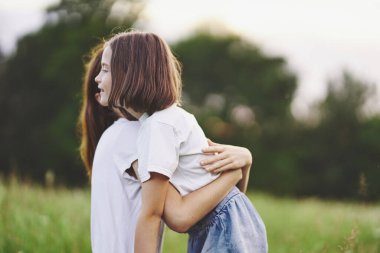 Genç anne ve kızı papatya tarlasında eğleniyorlar.
