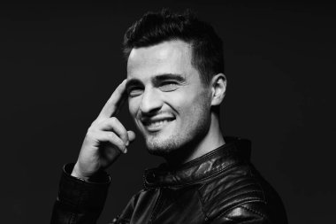 Stüdyoda poz veren siyah deri ceketli yakışıklı bir adamın portresi. Siyah ve beyaz  