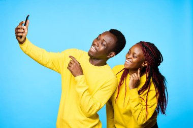 Genç ve güzel bir çift stüdyoda mavi arka planda selfie çekiyor.