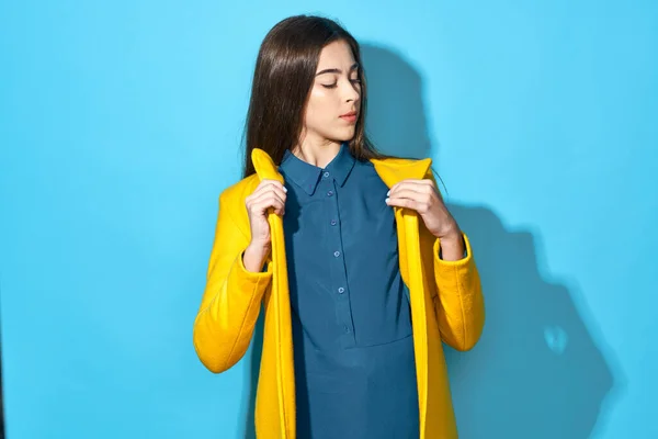 Stüdyoda Sarı Ceketli Genç Bir Kadın Mavi Arka Planda Izole — Stok fotoğraf