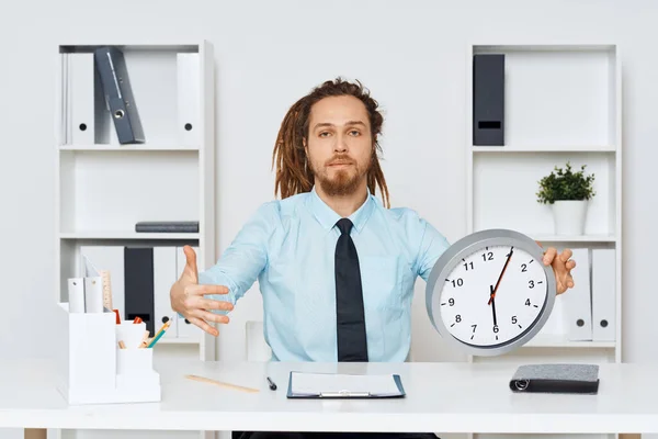 若いビジネスマンが大きな時計を持ってオフィスに座っている — ストック写真