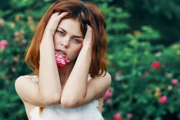 庭にバラの花を持つ若い女性 — ストック写真