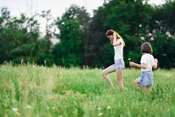 若いです母と彼女の娘持っています楽しいです上のカモミールフィールド — ストック写真