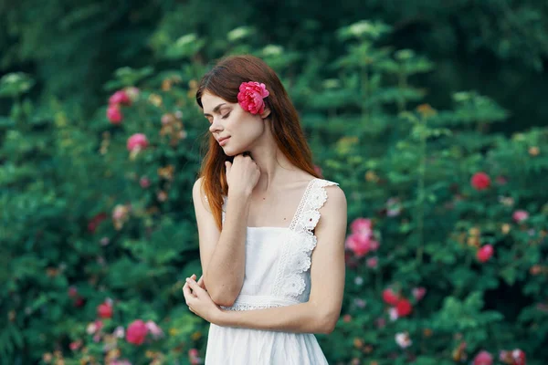 庭にバラの花を持つ若い女性 — ストック写真