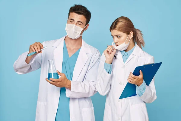 Stodio shot of young scientists in masks  with test tubes