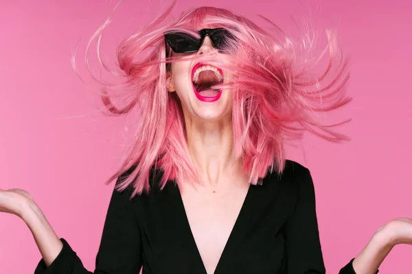 Young woman in pink wig  with blowing hair  on pink background