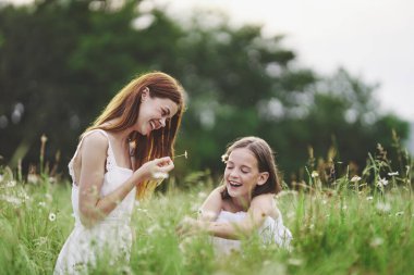 Genç anne ve kızı papatya tarlasında eğleniyorlar.