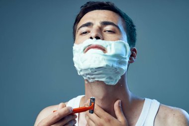 Stüdyo çekimi. Genç yakışıklı adam tıraş oluyor. 