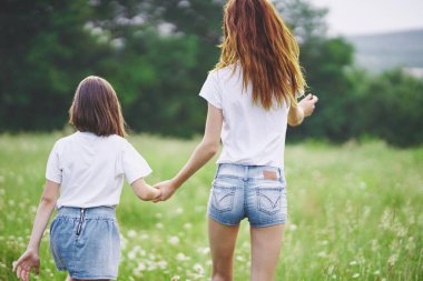 Genç anne ve kızı papatya tarlasında eğleniyorlar.