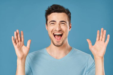 Mutlu genç adam stüdyoda mavi arka planda. 