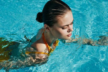 Genç ve güzel bir kadın havuzda dinleniyor.  