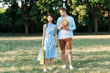 Parkta alışveriş torbaları olan genç bir çift.