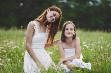 Genç anne ve kızı papatya tarlasında eğleniyorlar.