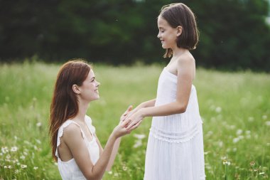 Genç anne ve kızı papatya tarlasında eğleniyorlar.