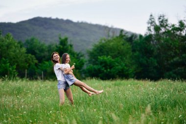 Genç anne ve kızı papatya tarlasında eğleniyorlar.