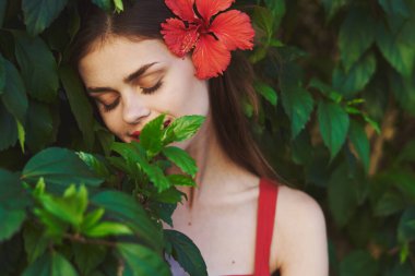 Saçında çiçekle poz veren güzel bir kadın.