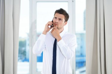 İş konsepti. Yong 'un kafası karışmış işadamı ofiste akıllı telefondan konuşuyor. 