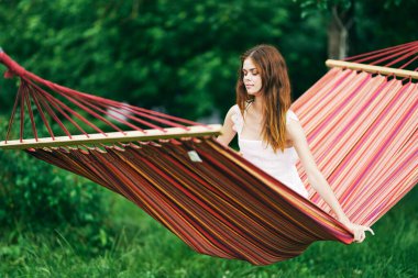 Genç ve güzel bir kadın hamakta dinleniyor.