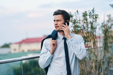Genç yakışıklı işadamı sokakta akıllı telefondan konuşuyor. 