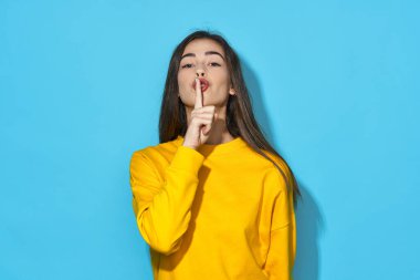 Stüdyoda, mavi arka planda izole edilmiş sessiz hareketlerle genç ve güzel bir kadın. 