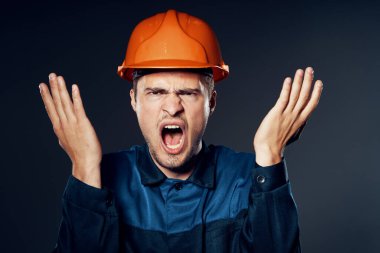Stüdyo çekimi. Turuncu kasklı genç işçi kızgın.
