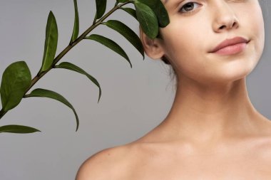 Stüdyoda yaprağıyla poz veren genç ve güzel bir kadın.