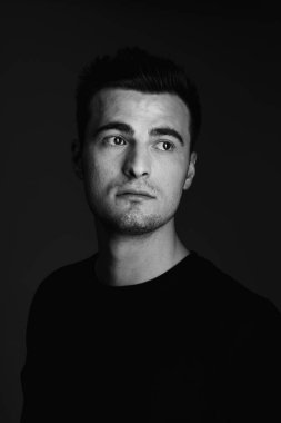 Siyah üzerinde poz veren yakışıklı bir adamın portresi. 