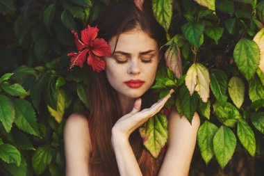 Saçında çiçekle poz veren güzel bir kadın.