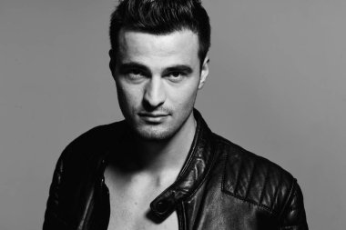 Stüdyoda poz veren siyah deri ceketli yakışıklı bir adamın portresi. Siyah ve beyaz  