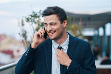 Genç yakışıklı işadamı sokakta akıllı telefondan konuşuyor. 