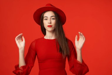 Stüdyo çekimi. Kırmızı şapkalı güzel kadın, kırmızı arka planda izole edilmiş.