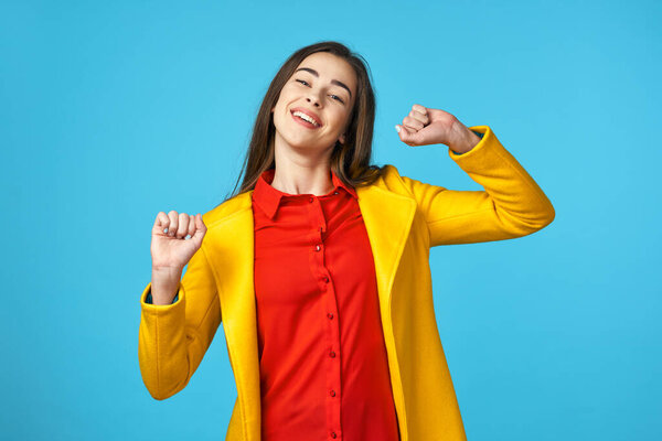 young beautiful woman in yellow jacket   smiling  in Studio with blue Background.