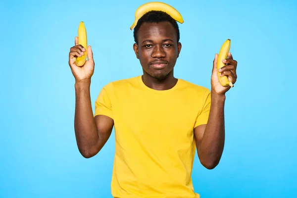 Young african man holding bananas   isolated on blue background