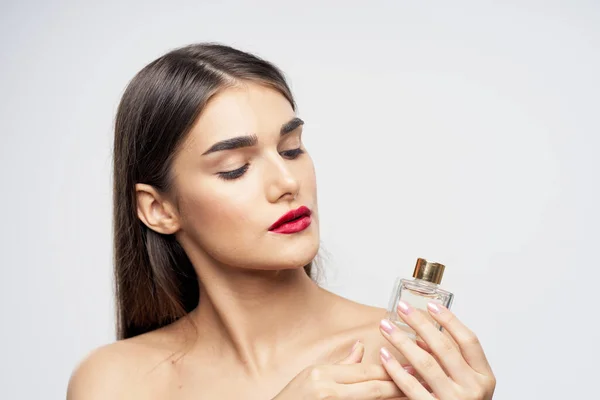 Portrait of young beautiful  woman with perfume bottle isolated on white background