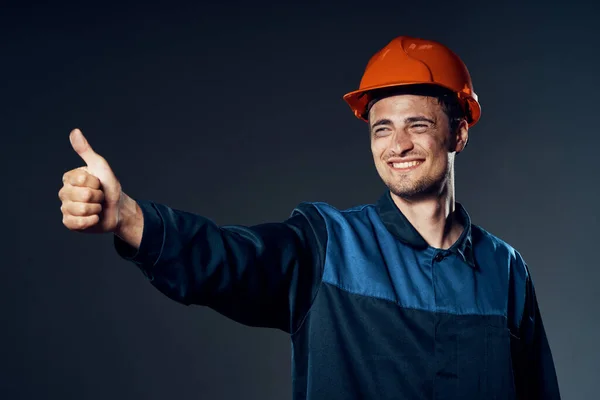 young man in work wear and helmet with thumb up. Studio shot