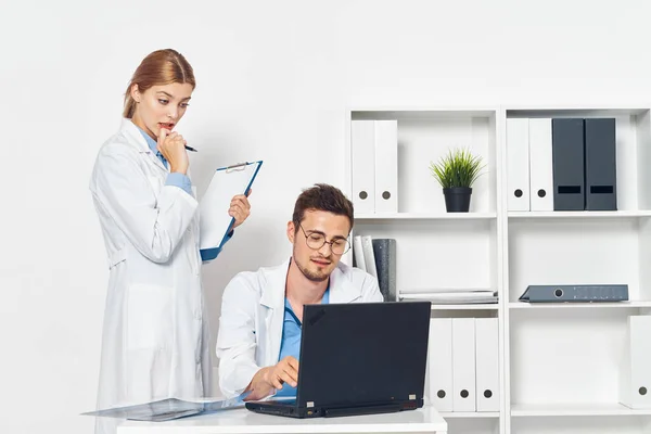 Young doctor with laptop  and nurse in hospital office