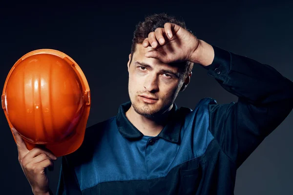 Studio shot. Young worker with  orange helmet is tired