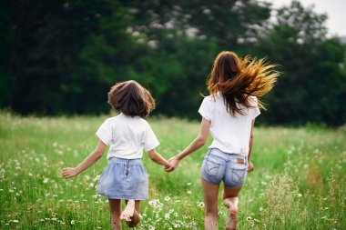 Genç anne ve kızı papatya tarlasında eğleniyorlar.