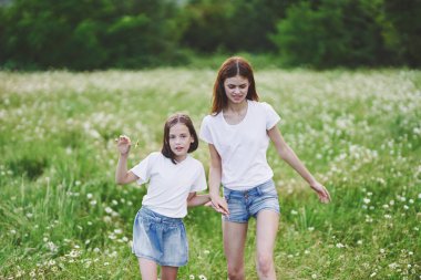 Genç anne ve kızı papatya tarlasında eğleniyorlar.