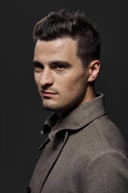 Koyu gri arka planda genç yakışıklı bir adamın portresi.  