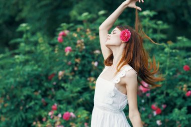 Bahçesinde gül çiçeği olan genç bir kadın