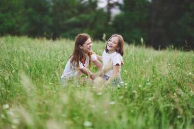 Genç anne ve kızı papatya tarlasında eğleniyorlar.