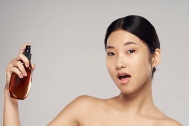 Stüdyoda saç spreyi kullanan Asyalı genç bir kadın. Güzellik, moda fotoğrafçılığı